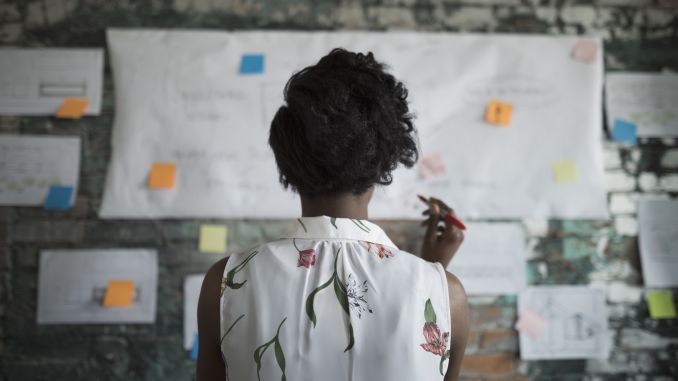 A girl in front of a board with a pen thinking