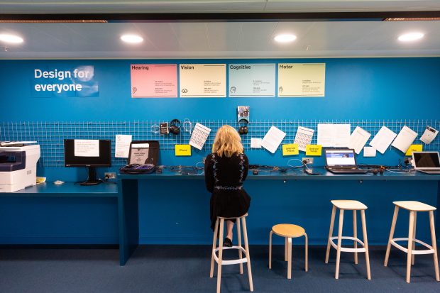 A girl working with computers and on the wall there is a poster says 