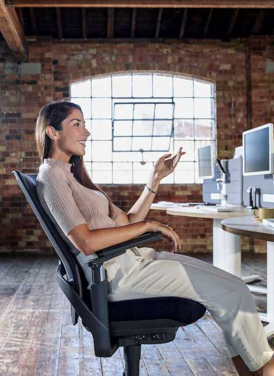 A girl sitting on a chair behind her desk smiling