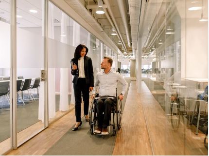 a guy on a wheelchair talking to a woman in the office