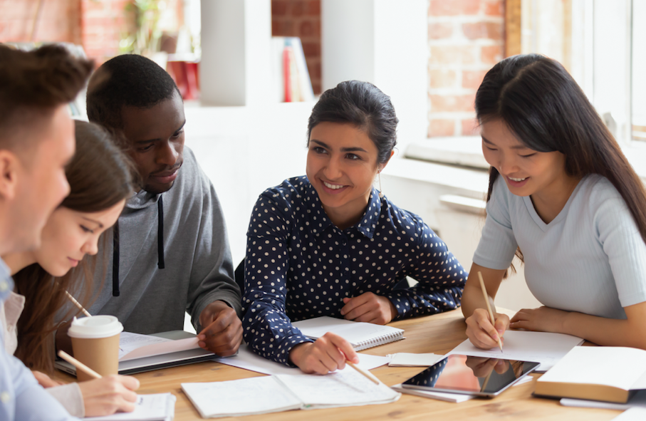 Focused multi national students sitting at desk studying together